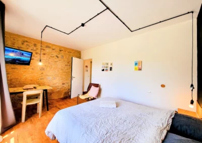 Chambre de Marius à La Maison Folia, maison d’hôtes en Normandie, avec lit double, bureau et mur en pierre