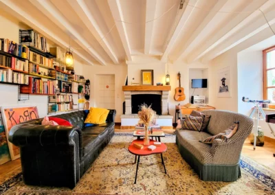 Salon spacieux de La Maison Folia avec canapé en cuir, bibliothèque, cheminée et coin détente en Normandie