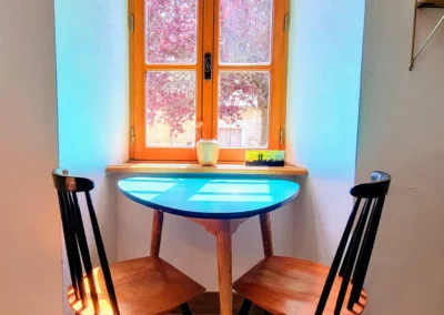 Coin repas avec table et chaises près de la fenêtre à La Maison Folia, maison d’hôtes en Normandie
