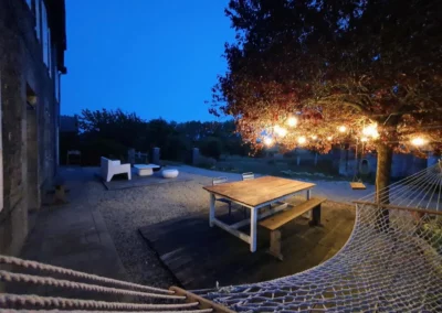 Terrasse de La Maison Folia le soir, maison d’hôtes en Normandie avec guirlandes lumineuses et hamac